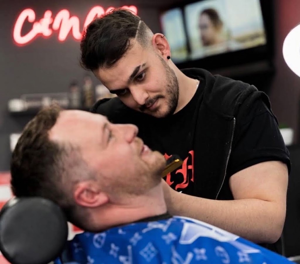 A barber carefully shaping a client’s beard with a straight razor